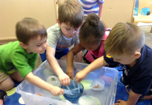 four children playing at water table